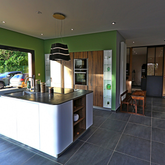 Cuisine blanche et bois avec un mur vert dans le showroom de L'Atelier du concepteur