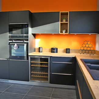 Une cuisine noire avec un plan de travail coloris bois dans le shworoom de L'Atelier du concepteur